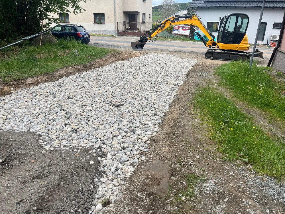 Minibagr na vysypaném štěrkovém podkladu u domu