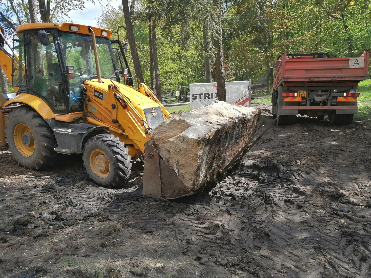 Traktorbagr s vidlemi a sklápěč při odvozu materiálu