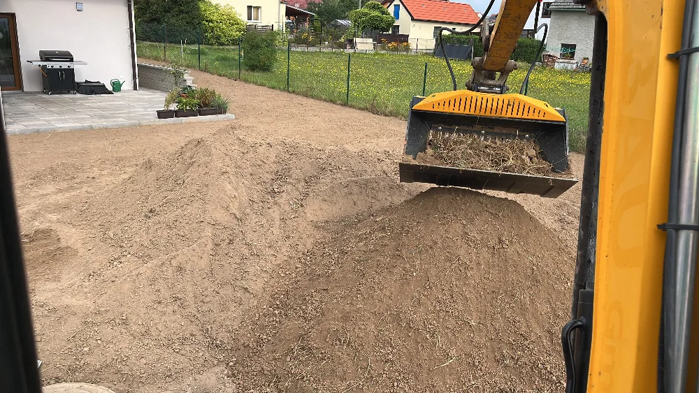 Bagr s hřídelovou rotační lžící při práci na pozemku
